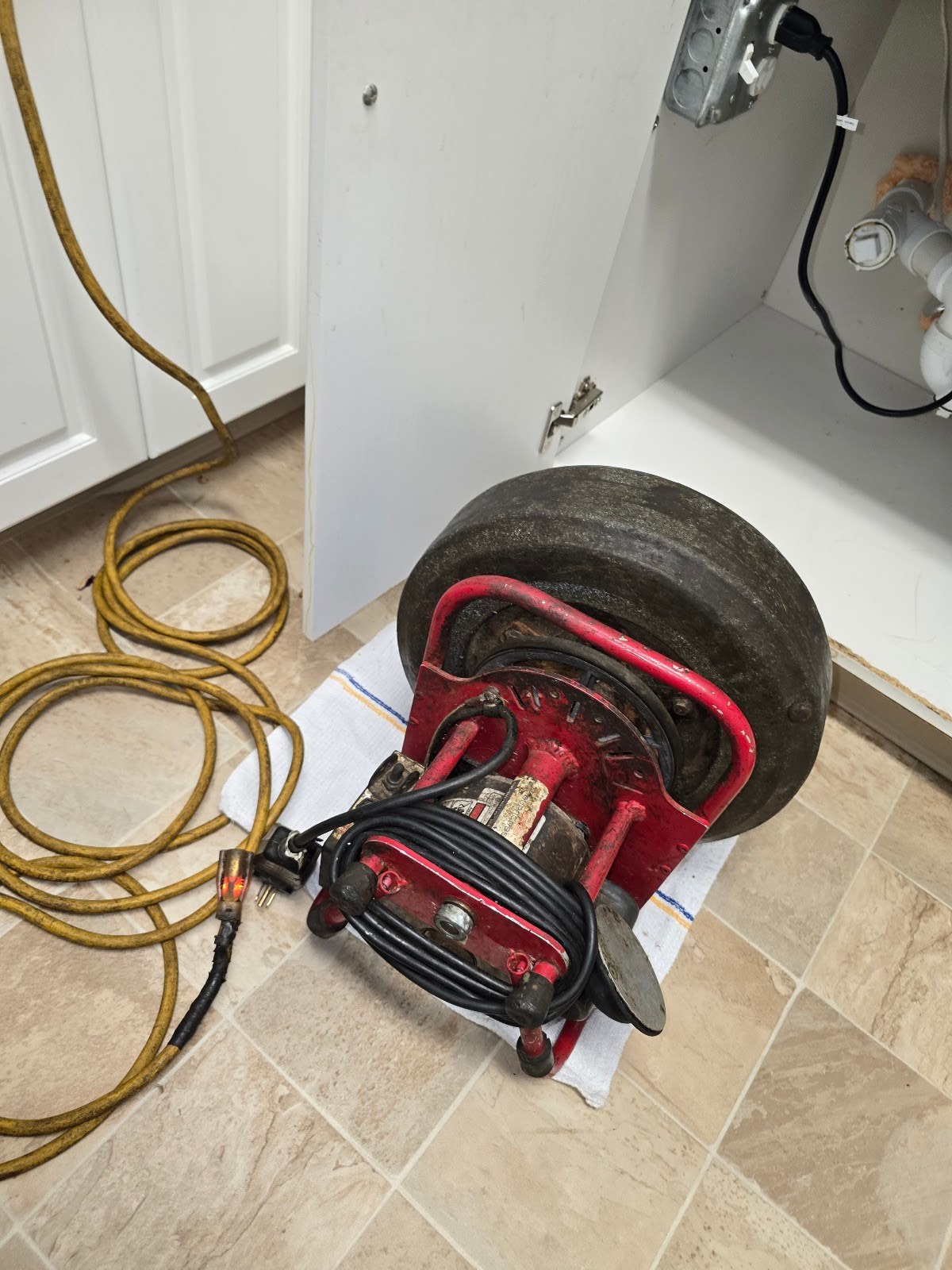 Drain cleaning machine set up on a drop cloth under a kitchen sink by Drain Polishers in Brockton, MA